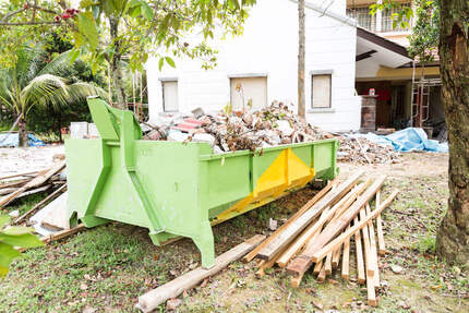image of a residential skip hire bin out the front of a house being demolished surrounded by timber planks
