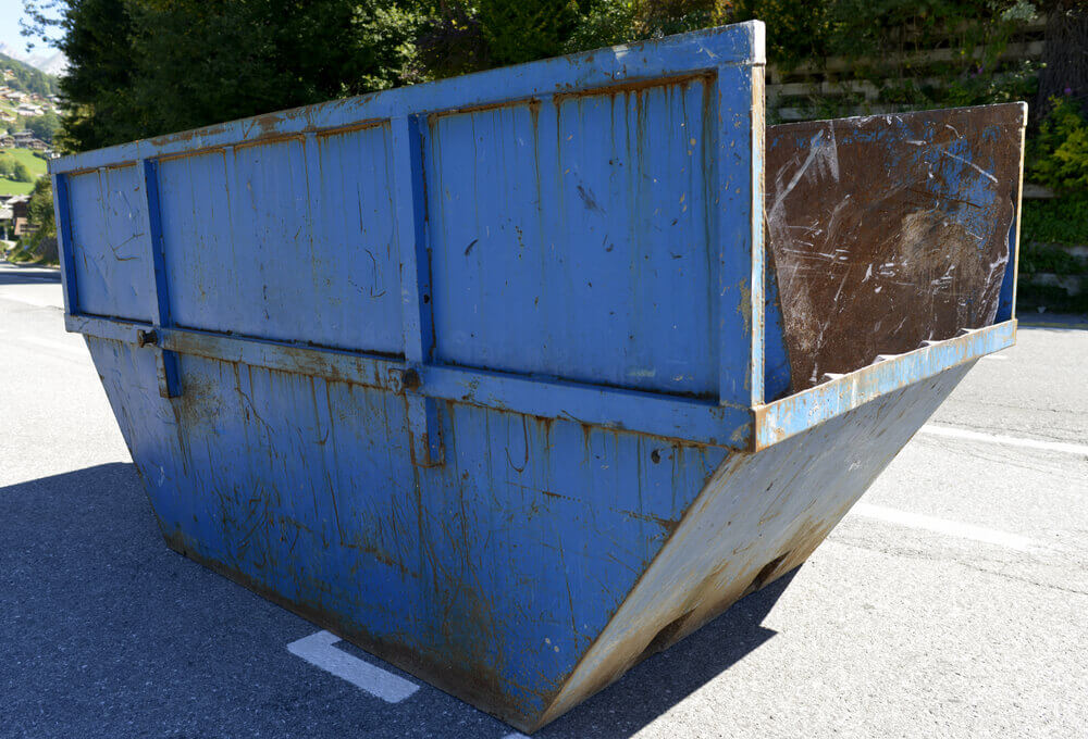 image of a blue residential skip hire bin with high sides sitting in the middle of a road